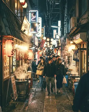 A narrow night alley of ramen shops lit by neon and paper lanterns, steam, fictional passers-by. With the Japan Film preset applied.