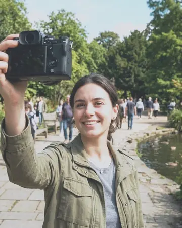 A fictional young woman taking a selfie in a park, clear day. With the Japan Film preset applied.