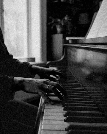 A fictional pianist's hands on the keys, room light. With the Mono Film preset applied.