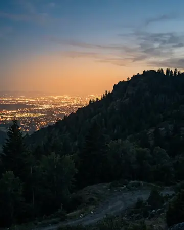 City light pollution glowing behind a dark hill, blue hour just after sunset, cool ambient light. Photographed without a preset.