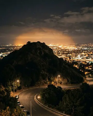 City light pollution glowing behind a dark hill, night, lit only by street and shop lights. Photographed without a preset.