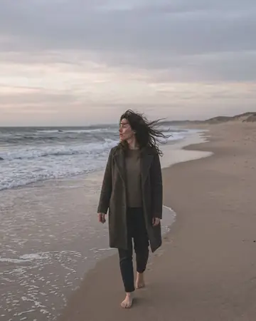 A fictional woman on an empty beach at dusk, wind in her hair. With the True Skin preset applied.